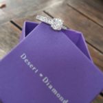 ring artistically displayed next to Desert Diamonds new purple gift box