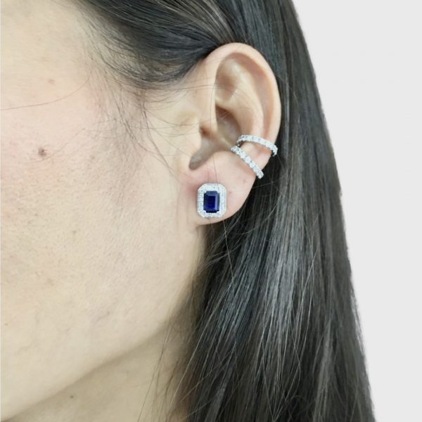 These elegant stud earrings feature a beautiful emerald cut (7x5mm) blue sapphire  simulant surrounded by a halo of round  (1.25mm) diamond simulants. 