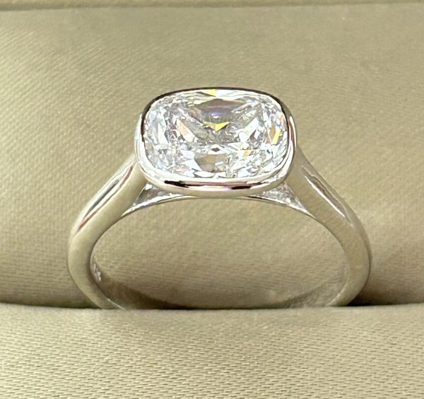 East-West Bezel Solitaire Ring with 9x7mm cushion-cut lab-created diamond simulant set in sterling silver with rhodium plating.